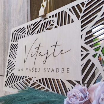 Uvítacia tabuľa na svadbu z dreva s nápisom ‚Vitajte na našej svadbe‘, ozdobená kvetmi a pampovou trávou – elegantný doplnok svadobnej výzdoby.