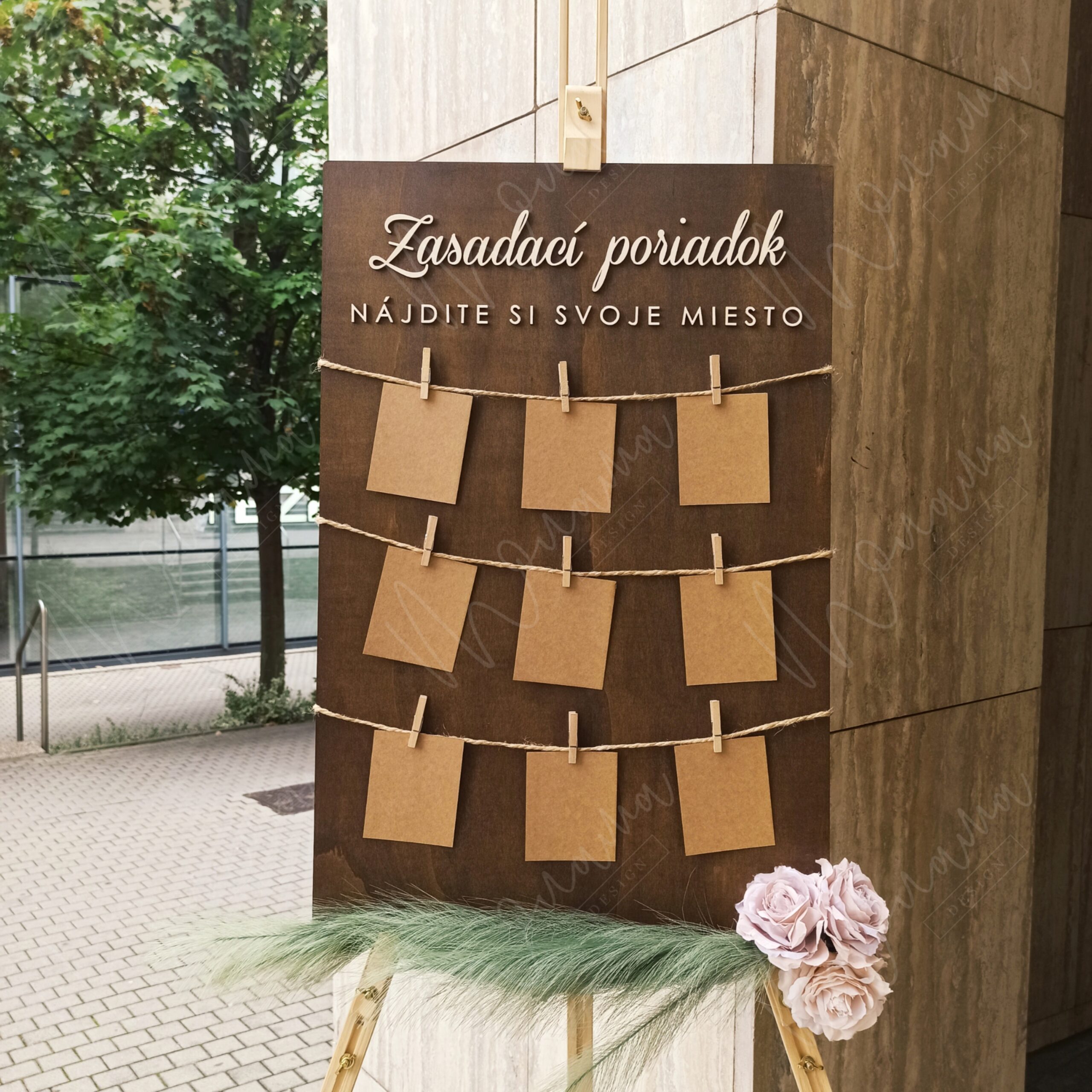 Rustikálny drevený zasadací poriadok so špagátom, drevenými kolíčkami a kraft kartičkami — seating chart na svadbu a event.