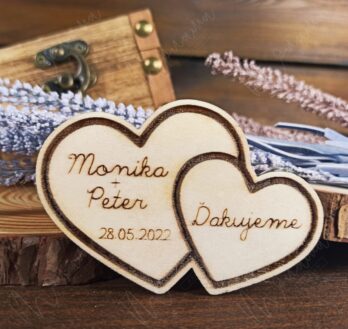 Drevená svadobná magnetka v tvare dvoch prepojených sŕdc s gravírovanými menami „Monika + Peter“, dátumom svadby „28.05.2022“ a poďakovaním „Ďakujeme“. Elegantný a rustikálny svadobný darček pre hostí, vyrobený z prírodného dreva s magnetom na zadnej strane.