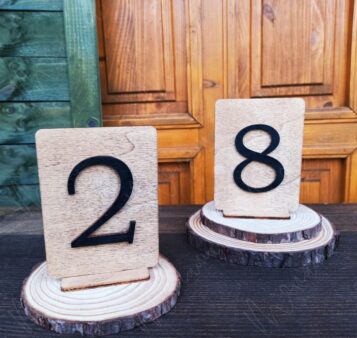 Rustikálne drevené čísla na svadobný stôl – prírodná dekorácia s čiernymi číslicami.