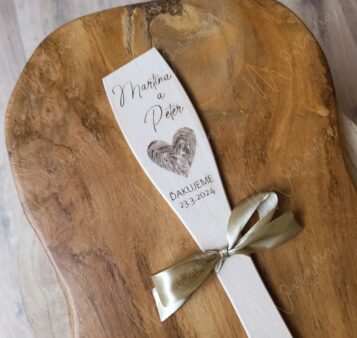Drevená vareška s gravírovaným motívom a menami ozdobená saténovou stuhou.