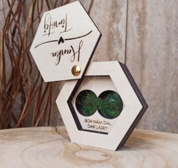 Personalizovaná drevená krabička na obrúčky s gravírovaným nápisom 'Boh nám dal dar lásky' a machovým detailom.