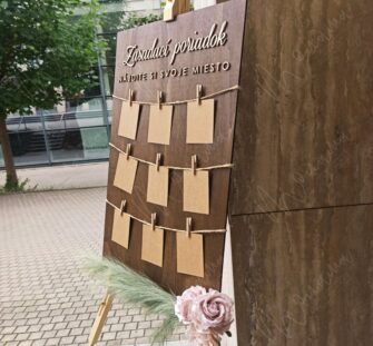 Zasadací poriadok — rustikálny drevený seating chart na svadbu Rustikálny drevený zasadací poriadok so špagátom, drevenými kolíčkami a kraft kartičkami — seating chart na svadbu a event.